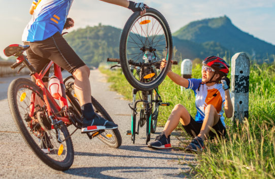Cyclists on the side of a road changing a tire