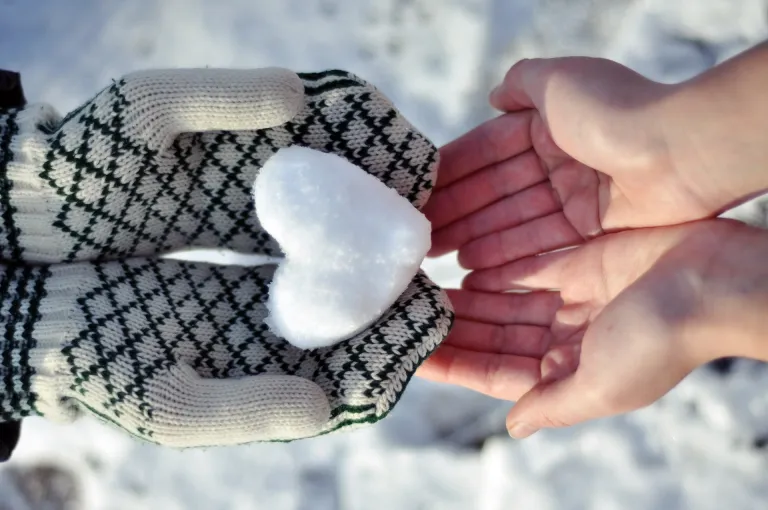 Two people in the snow one passing another one snow shaped like a heart